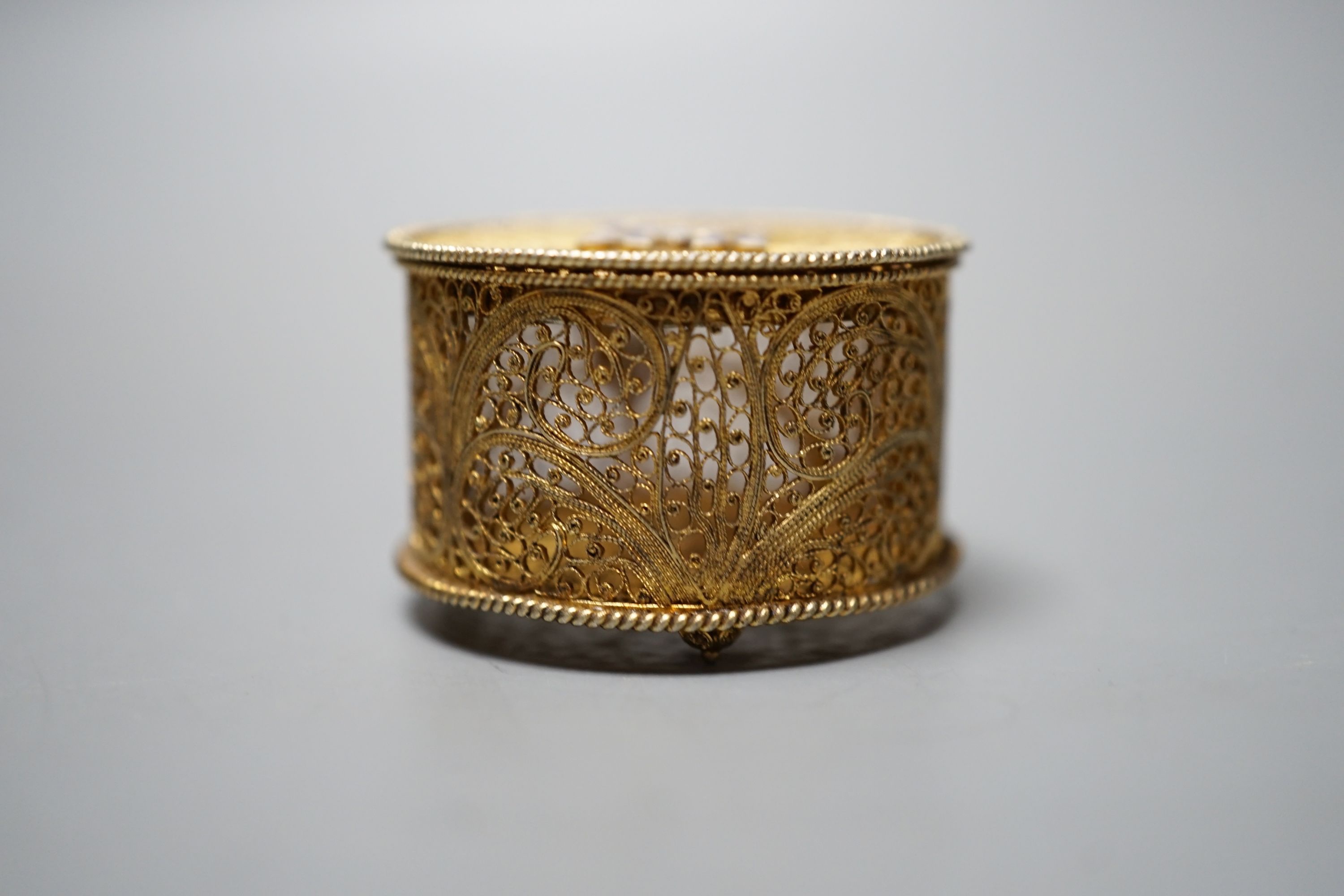 A late 19th/early 20th century Portuguese gilt white metal filigree and two colour enamel circular pill box, 35mm.
